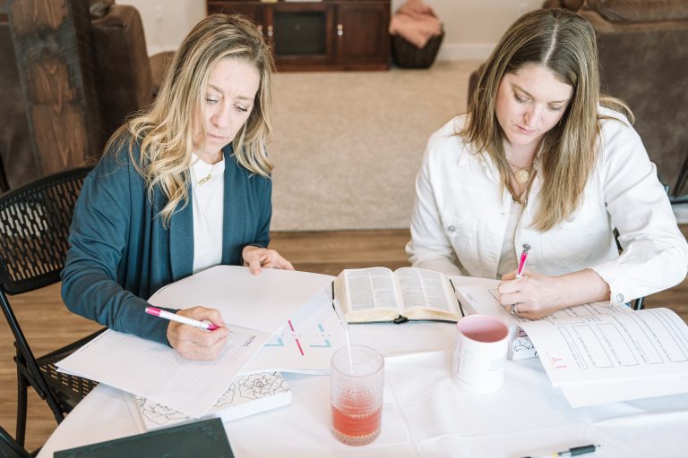 Two women studying Scripture and journaling at a table